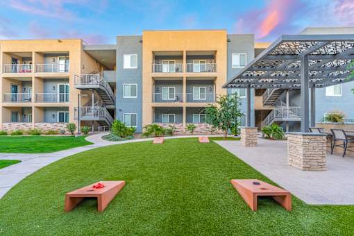 A modern apartment complex with a well-maintained lawn and seating area.