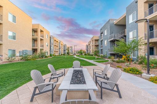 A patio with a table and chairs is surrounded by apartment buildings.