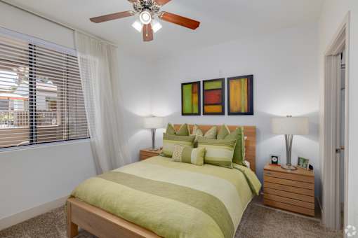 A bedroom with a bed, nightstand, and a ceiling fan.