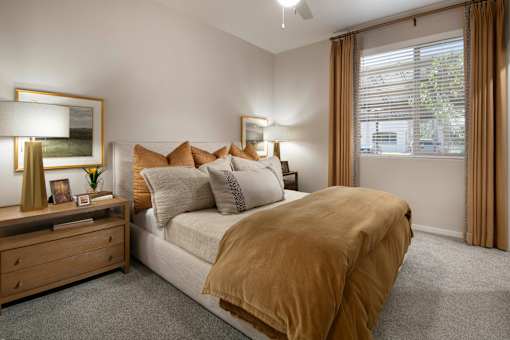 A bedroom with a bed, nightstand, and window.