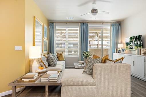 A living room with a beige sofa, a wooden coffee table, and a ceiling fan.