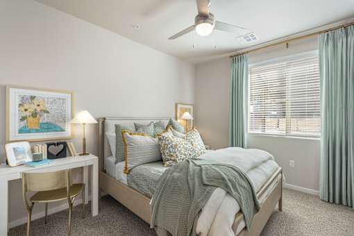 A bedroom with a bed, desk, chair, and window.