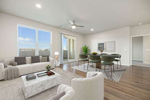 A modern living room with a white sofa, a coffee table, and a dining table set up.