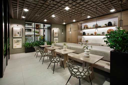 A restaurant with tables and chairs and a plant in a planter.
