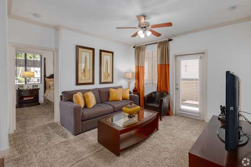 A living room with a brown couch and a ceiling fan.