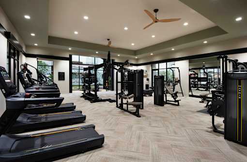 A spacious gym with treadmills, weights, and a ceiling fan.