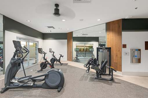 A gym with a variety of exercise equipment including treadmills, stationary bikes, and weight machines.
