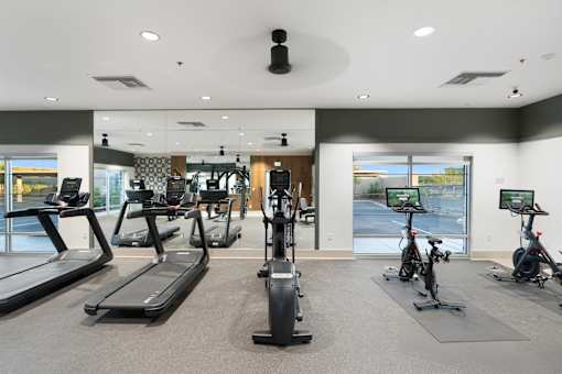 A gym with treadmills, exercise bikes, and a television.