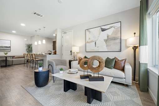 A modern living room with a white sofa, a coffee table, and a large abstract painting on the wall.