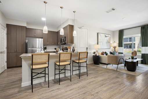 A modern kitchen with wooden floors and a large island with two chairs.