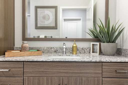 A bathroom vanity with a marble countertop and wooden drawers.