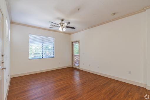 A room with a ceiling fan and wooden flooring.