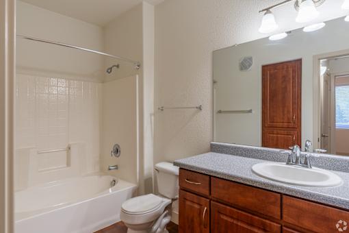 A bathroom with a white tub, sink, and toilet.