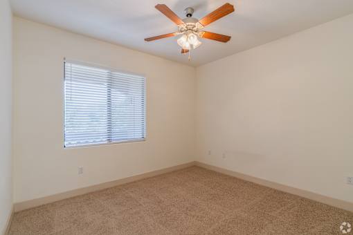 A room with a ceiling fan and a window with blinds.