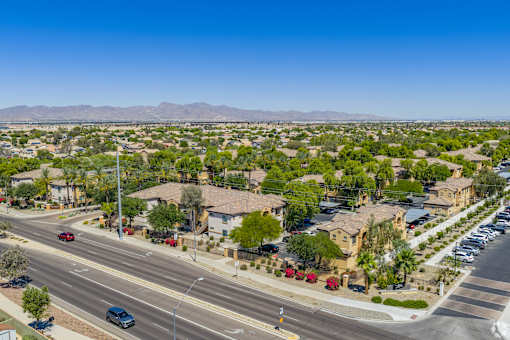 A suburban street with cars and houses under a clear blue sky.