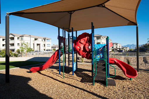 A playground with a red slide and a canopy.