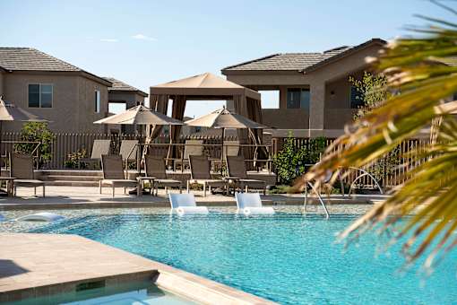 A pool area with a few chairs and umbrellas.