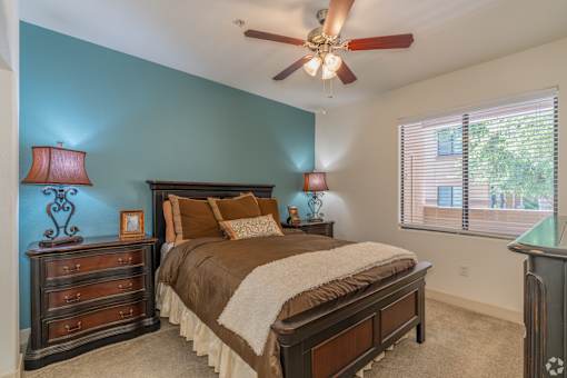 A bedroom with a bed, dresser, and ceiling fan.