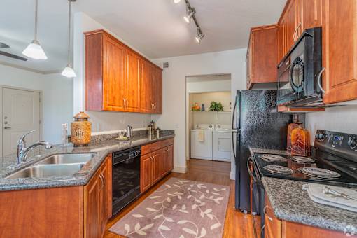 A kitchen with wooden cabinets and a black refrigerator.