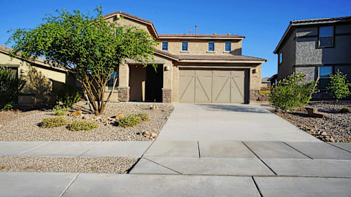 A house with a brown garage door and a tree in front.