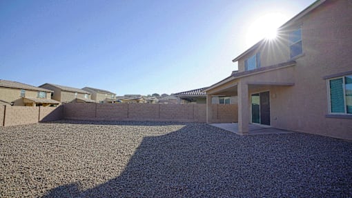 A sunny day in a residential area with houses and a gravel driveway.