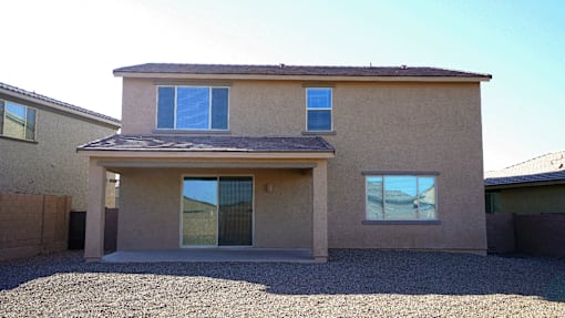 A house with a brown stucco exterior and a gravel driveway.