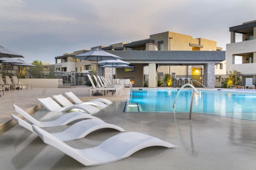 a pool with white lounge chairs and umbrellas