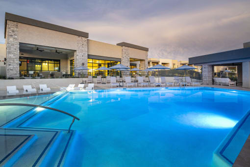 a large swimming pool with lounge chairs and umbrellas