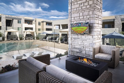 an outdoor patio with a fireplace and a pool in the background