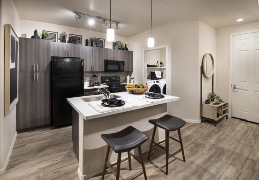 a kitchen with a large island and a black refrigerator