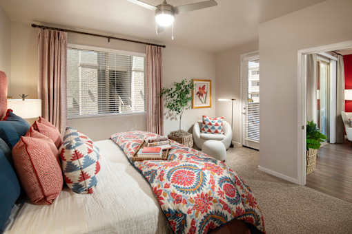 A bedroom with a bed, a chair, and a ceiling fan.