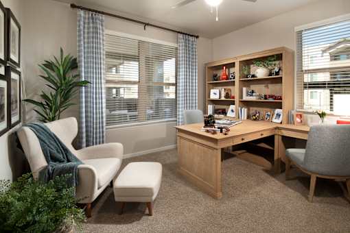 A room with a desk, chairs, and a bookshelf.