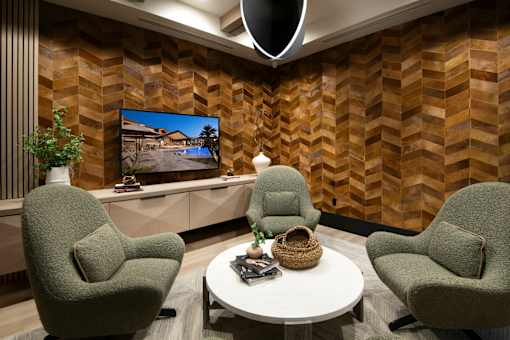 A modern living room with a large screen TV and two green armchairs.