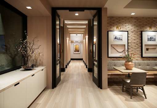 A long, narrow hallway with a bench and a table with a vase on it.