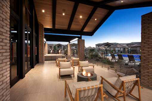 A patio with a fire pit and chairs.