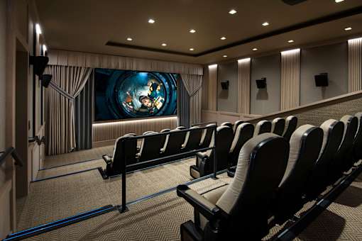 A movie theater with rows of seats facing a large screen.