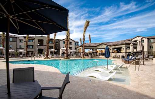 A pool area with a table and chairs and umbrellas.