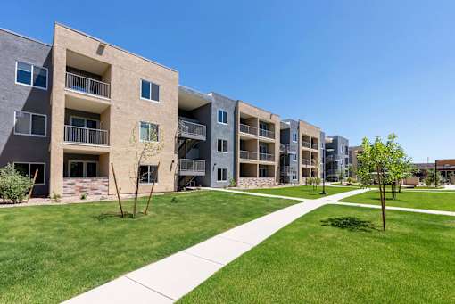 A row of modern apartment buildings with a walkway in the foreground.