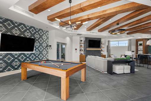 A pool table is in the middle of a room with a television and a couch.