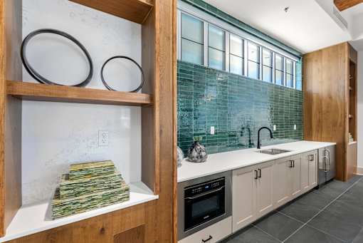 A kitchen with a white counter top and a green tile backsplash.