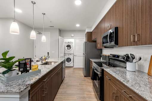 A modern kitchen with dark wood cabinets and granite countertops.