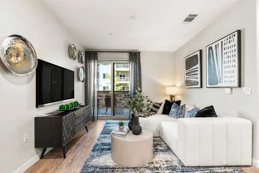 A living room with a white couch, a black cabinet, and a television.