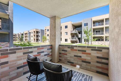 Two black chairs are on a patio with a brick wall.