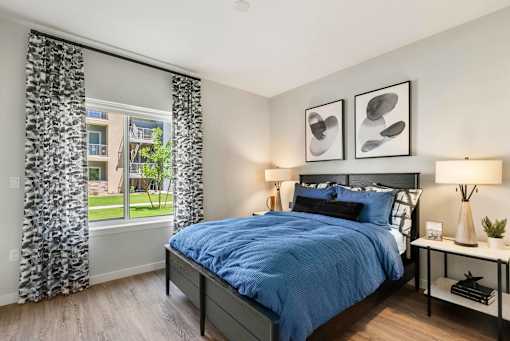 A bedroom with a large bed and a window with curtains.