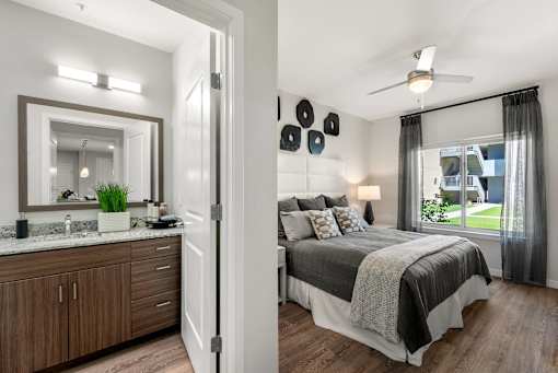 A bedroom with a bed, a vanity, and a window.