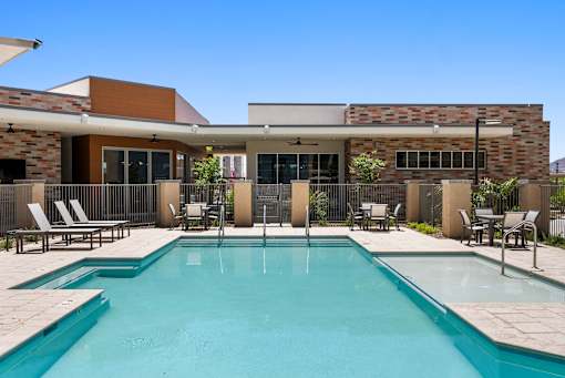 A swimming pool in front of a house with a fence around it.