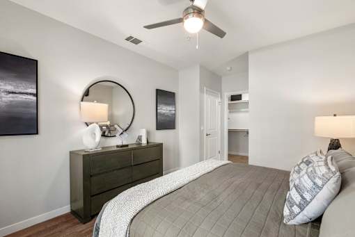 A bedroom with a bed, dresser, and ceiling fan.