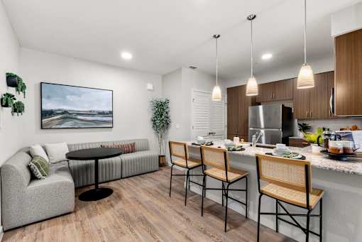 A modern kitchen with a grey couch and a painting on the wall.