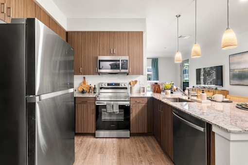 A modern kitchen with a refrigerator on the left and a sink on the right.