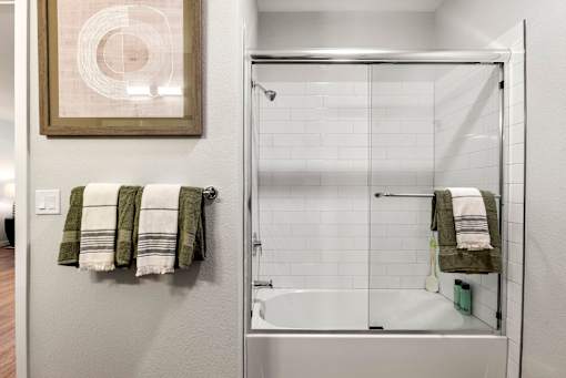 A bathroom with a white tiled shower and a white bathtub.